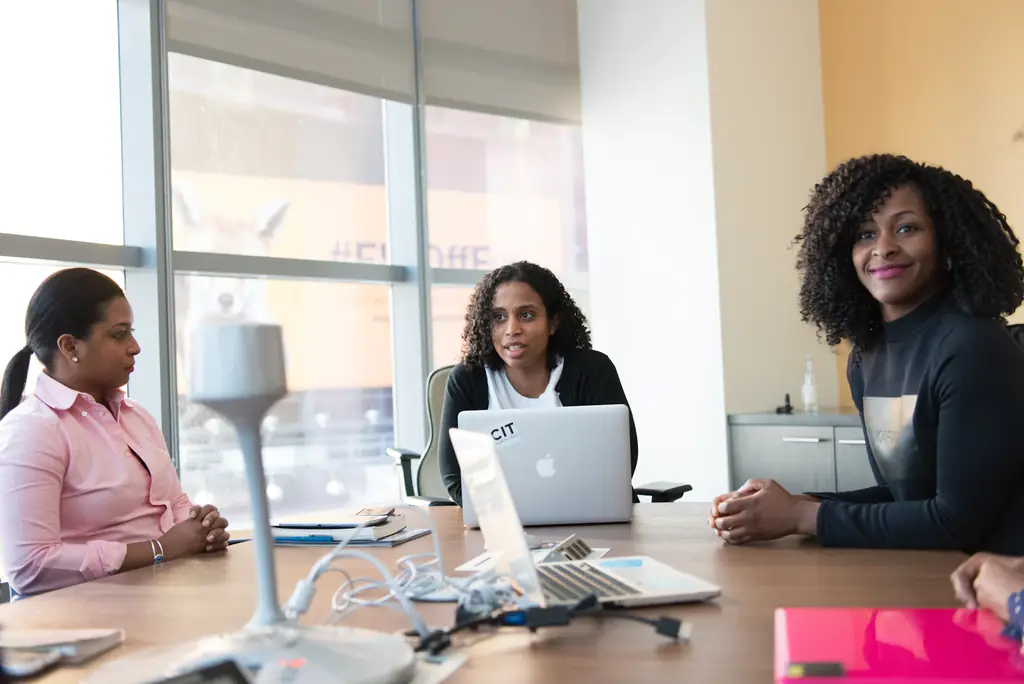 Trois professionnelles échangent autour d'une table de réunion