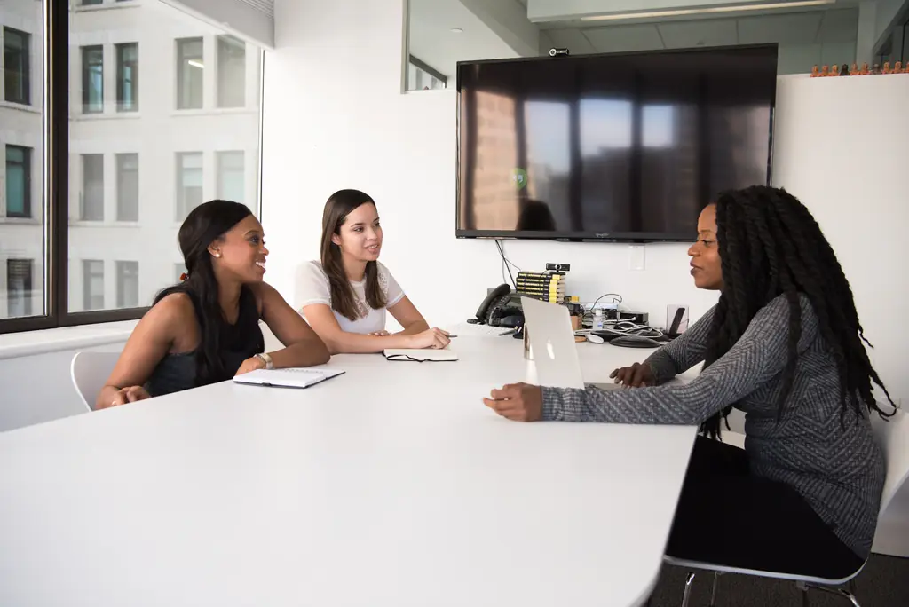 Trois femmes en réunion de travail dans une salle claire